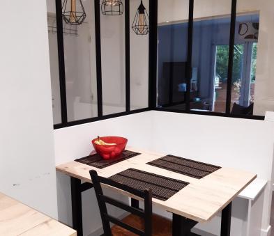 Création d'un espace repas avec une table sur mesure réalisé par un plan de travail en stratifié et piètement en métal. Banc composé de meubles de cuisine à tiroir et plan de travail