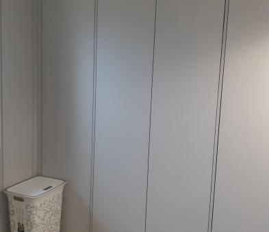Aménagement sur mesure dans une salle de bain réalisé en mélaminé gris clair de chez IN IPSO avec portes battantes sur charnières invisibles, ouverture par système pusch to open (sans poignée)